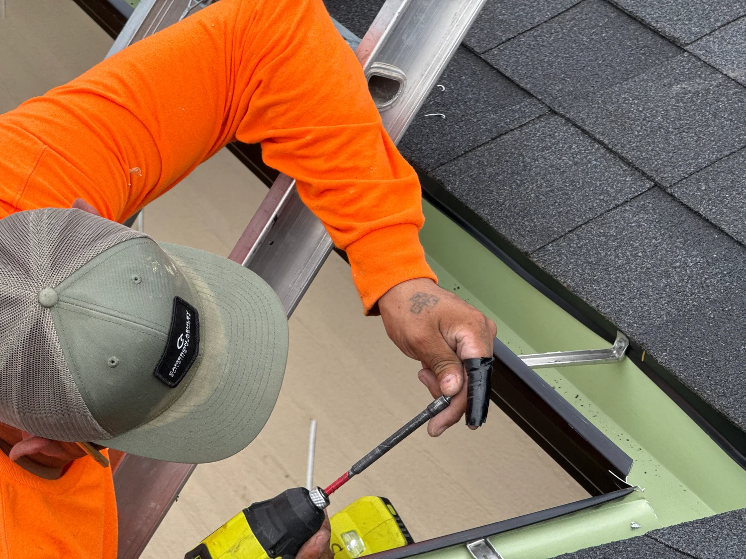 Thermal Shop installer fastening a hanger inside a new seamless gutter at the edge of the roof